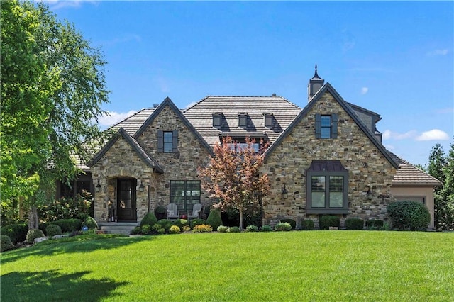 tudor home with an attached garage and a front yard