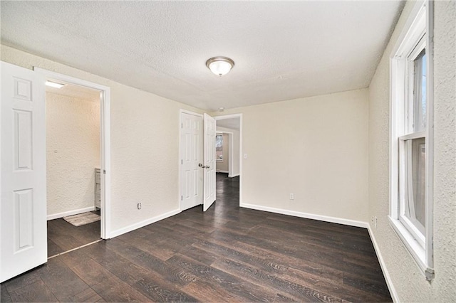 unfurnished room featuring dark hardwood / wood-style flooring and a textured ceiling