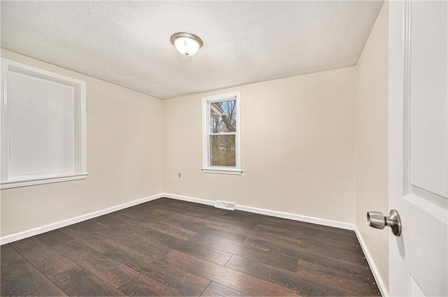 spare room featuring dark hardwood / wood-style flooring and a textured ceiling