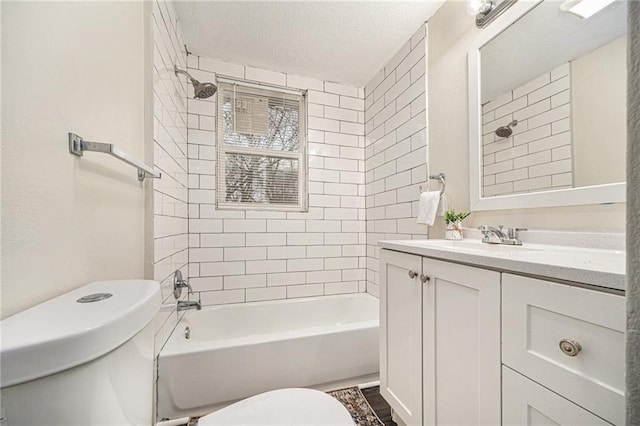 full bathroom featuring tiled shower / bath, vanity, toilet, and a textured ceiling