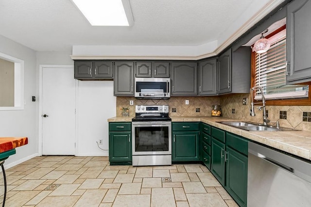 kitchen with appliances with stainless steel finishes, sink, backsplash, and green cabinetry