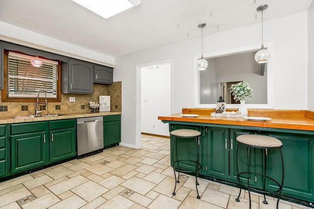 kitchen with butcher block countertops, decorative light fixtures, sink, stainless steel dishwasher, and green cabinetry