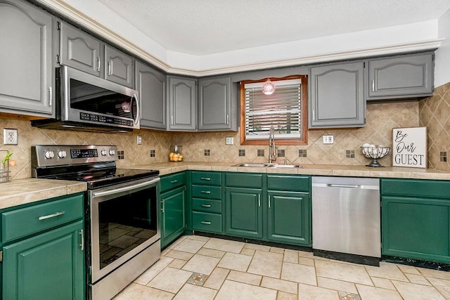 kitchen featuring stainless steel appliances, sink, backsplash, and green cabinetry