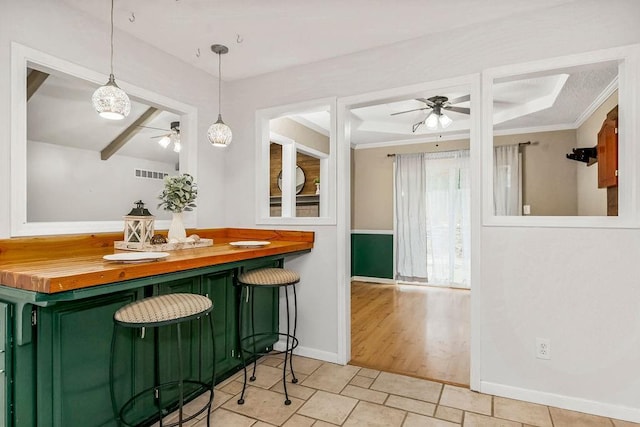 interior space with wood counters, hanging light fixtures, green cabinetry, and ceiling fan