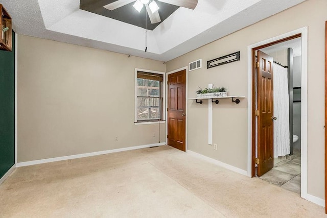 carpeted spare room featuring ceiling fan and a tray ceiling