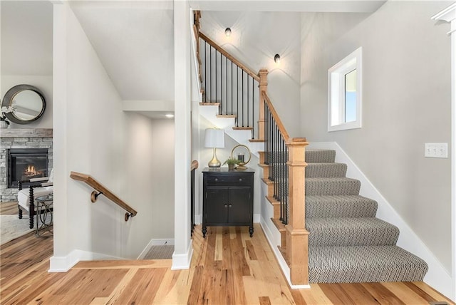 stairs with hardwood / wood-style flooring, a fireplace, and vaulted ceiling