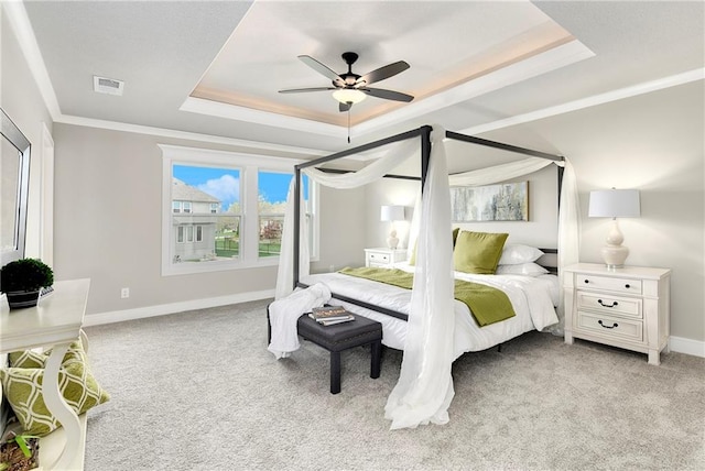 carpeted bedroom featuring a tray ceiling, ornamental molding, and ceiling fan