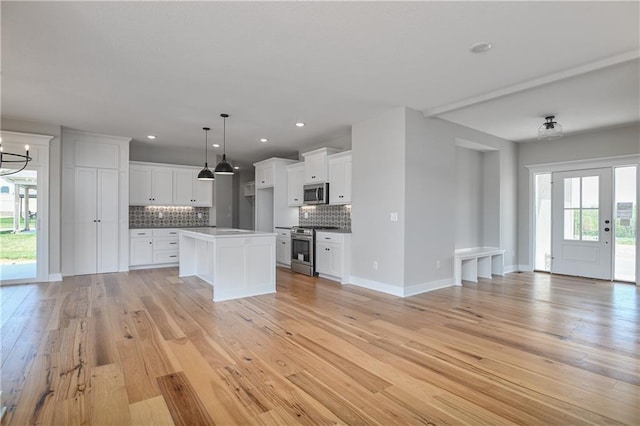 kitchen featuring a kitchen island, decorative light fixtures, white cabinets, decorative backsplash, and stainless steel appliances