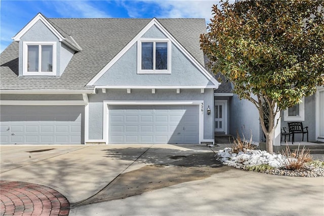 view of front of house with concrete driveway, a shingled roof, and stucco siding