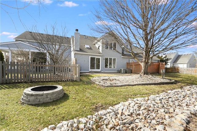 back of house featuring a fire pit, a lawn, a chimney, fence, and a gazebo