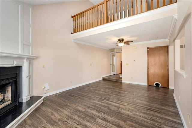 unfurnished living room with wood finished floors, a ceiling fan, a high end fireplace, baseboards, and ornamental molding