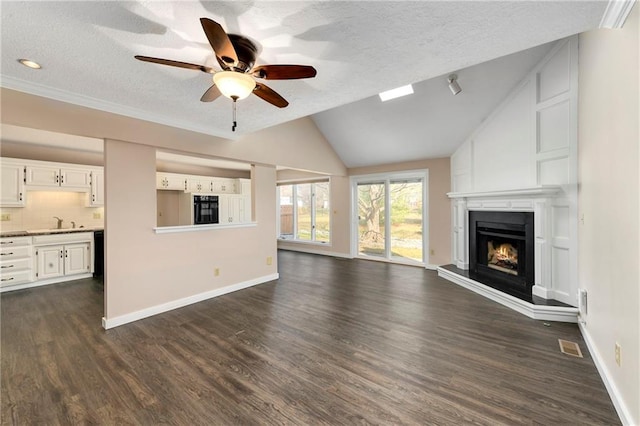 unfurnished living room featuring dark wood finished floors, a fireplace, lofted ceiling, and baseboards