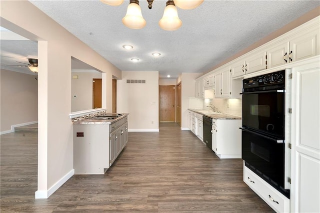 kitchen featuring dark wood-type flooring, a sink, visible vents, backsplash, and black appliances