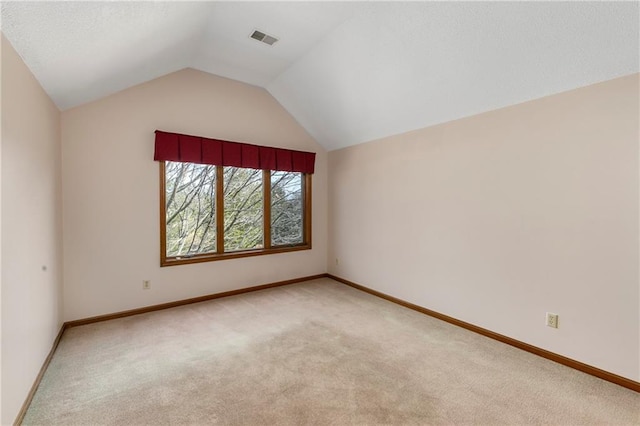 interior space featuring light carpet, vaulted ceiling, visible vents, and baseboards