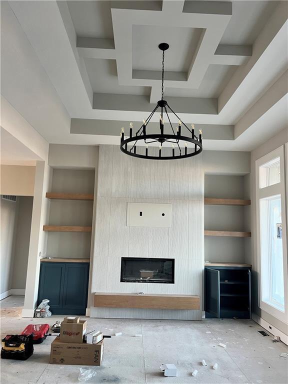 unfurnished living room with coffered ceiling, built in features, and an inviting chandelier