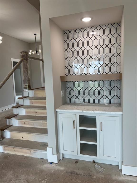 2209 W 176th Pl, Overland Park, KS 66085 - bar featuring a chandelier, stairway, concrete floors, and decorative light fixtures