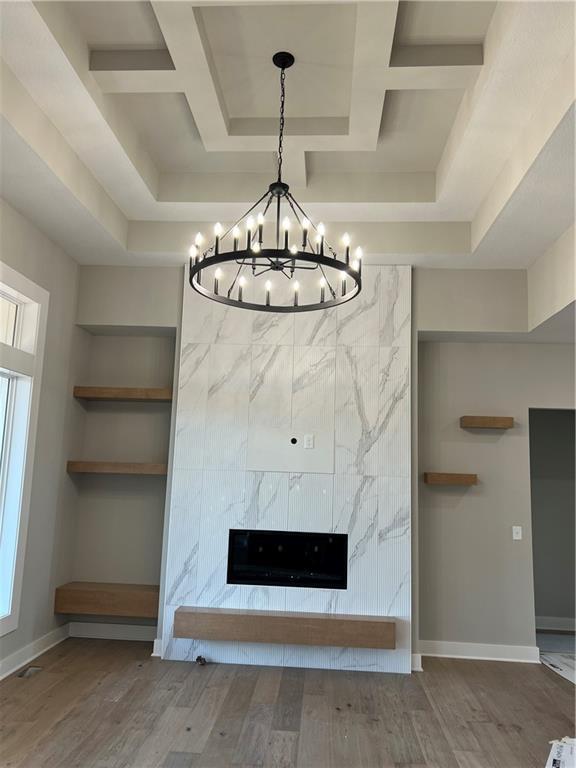 2209 W 176th Pl, Overland Park, KS 66085 - detailed view of a chandelier, wood finished floors, a tray ceiling, a fireplace, and built in shelves