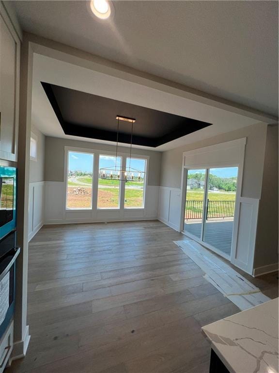 2209 W 176th Pl, Overland Park, KS 66085 - unfurnished dining area with a raised ceiling, a decorative wall, a wainscoted wall, wood-type flooring, and healthy amount of natural light