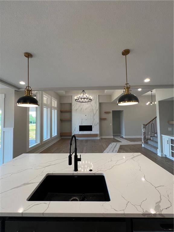 2209 W 176th Pl, Overland Park, KS 66085 - kitchen with open floor plan, light wood-style floors, a high end fireplace, decorative light fixtures, and a textured ceiling