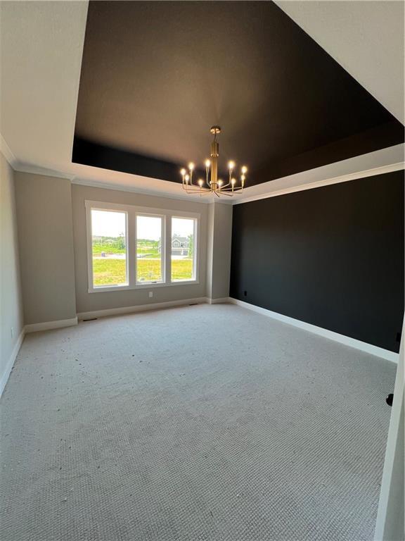 2209 W 176th Pl, Overland Park, KS 66085 - spare room featuring a chandelier, a tray ceiling, light carpet, and crown molding