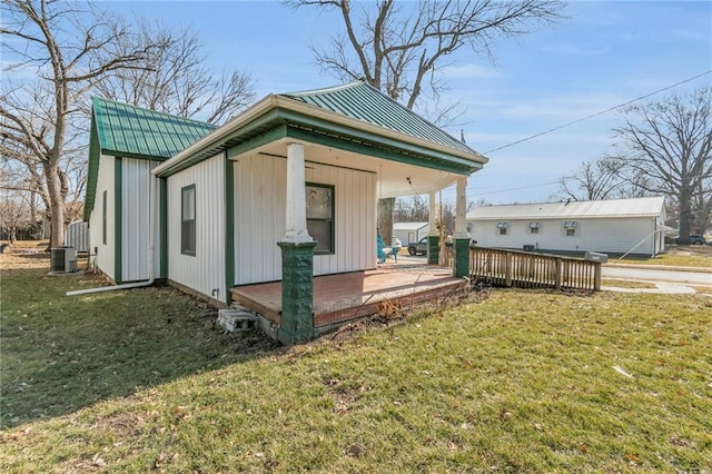 view of side of home featuring a wooden deck, a yard, central AC unit, and an outbuilding