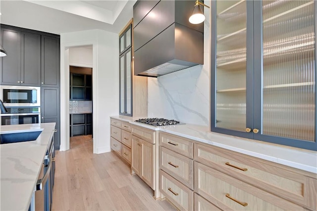 24909 W 98th Pl, Lenexa, KS 66227 - kitchen with stainless steel appliances, light wood-style flooring, wall chimney exhaust hood, tasteful backsplash, and light stone counters