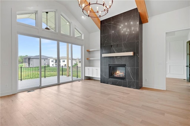 24909 W 98th Pl, Lenexa, KS 66227 - unfurnished living room featuring a chandelier, high vaulted ceiling, wood finished floors, a fireplace, and built in shelves