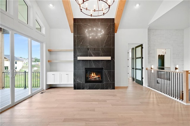 24909 W 98th Pl, Lenexa, KS 66227 - unfurnished living room with a chandelier, plenty of natural light, light wood-style flooring, a towering ceiling, and a fireplace