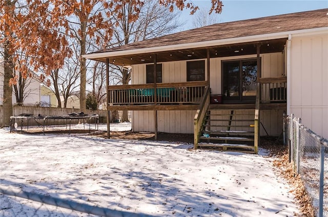 view of front of home with a trampoline, fence, and stairway