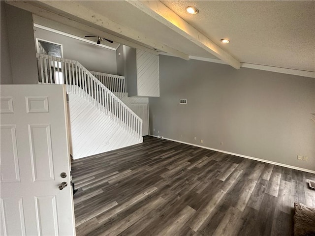 interior space featuring vaulted ceiling with beams, dark wood-type flooring, and a textured ceiling