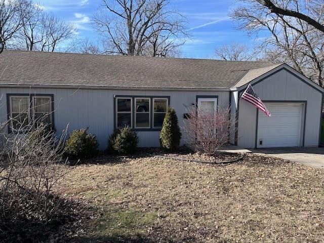 ranch-style house with concrete driveway, a shingled roof, and an attached garage