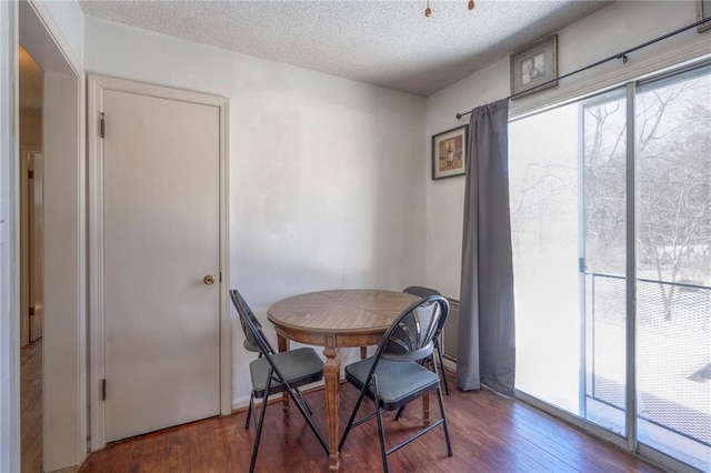 dining room with a textured ceiling, dark wood finished floors, and a healthy amount of sunlight