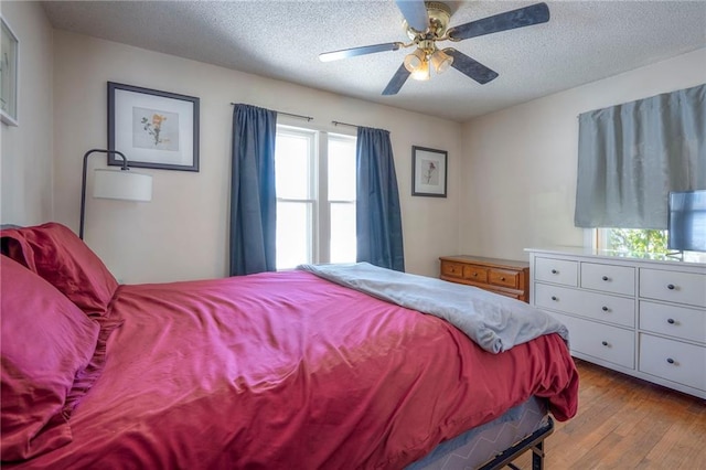 bedroom featuring light wood-style flooring, ceiling fan, and a textured ceiling