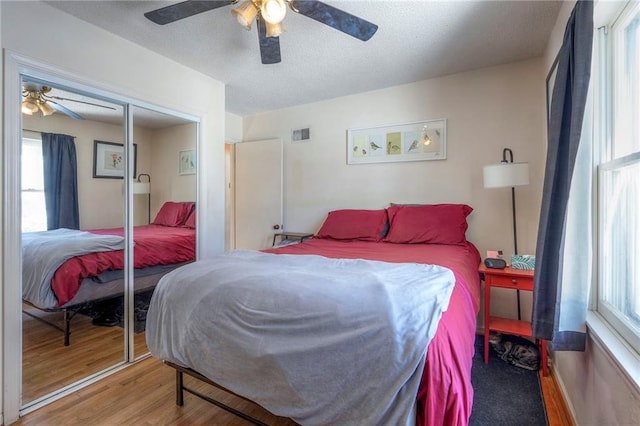 bedroom with a closet, visible vents, a ceiling fan, a textured ceiling, and wood finished floors