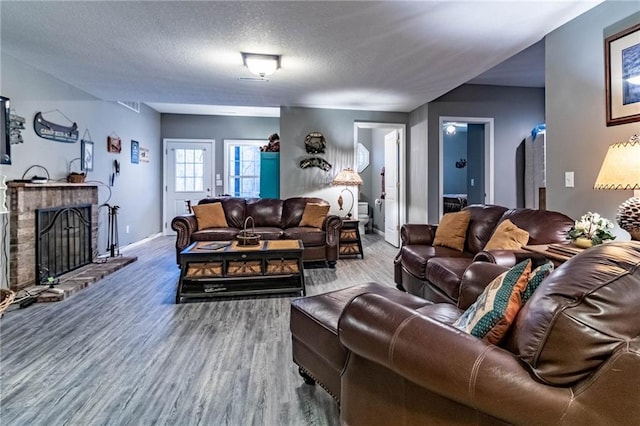 living room with hardwood / wood-style flooring, a fireplace, and a textured ceiling