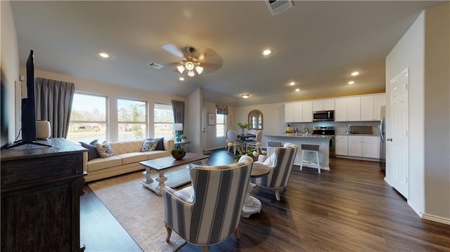 living room featuring dark wood-type flooring and ceiling fan