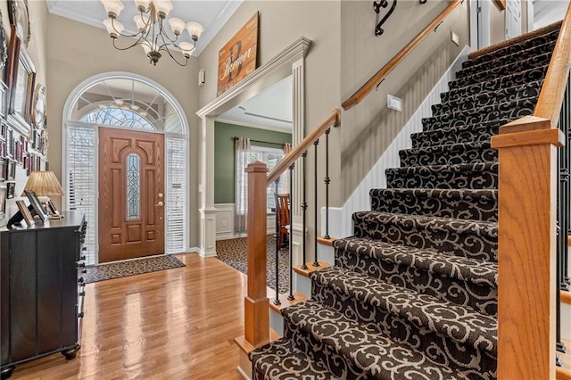 entrance foyer with light wood finished floors, plenty of natural light, a high ceiling, and crown molding