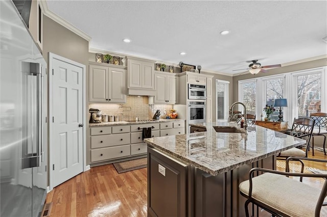 kitchen with light stone countertops, crown molding, stainless steel appliances, and a sink