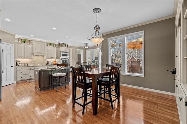 dining room featuring baseboards, ornamental molding, light wood-style flooring, and recessed lighting