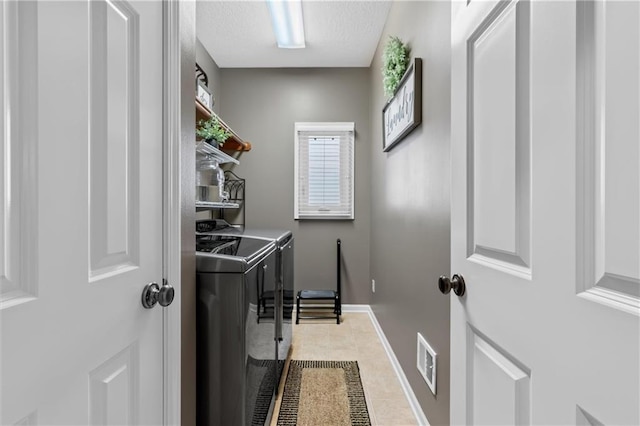 clothes washing area featuring washing machine and clothes dryer, visible vents, light tile patterned flooring, laundry area, and baseboards