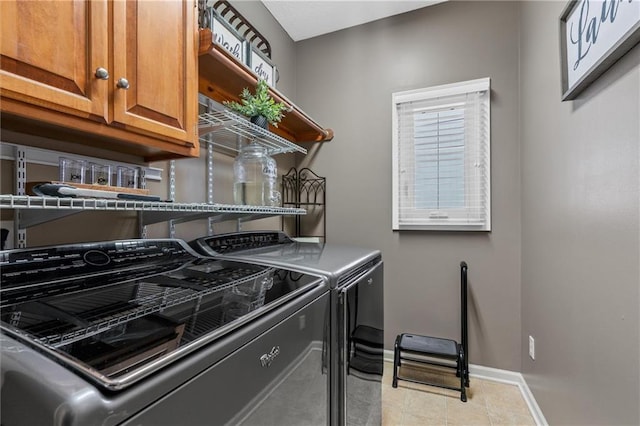 laundry room featuring washing machine and dryer, cabinet space, baseboards, and light tile patterned flooring