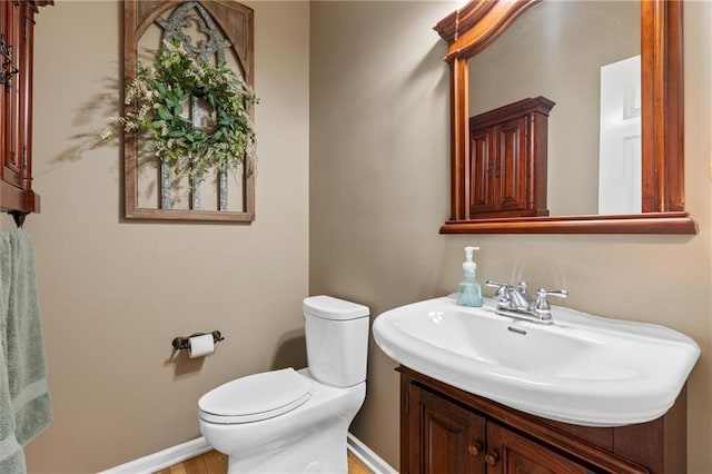 bathroom featuring toilet, baseboards, and a sink