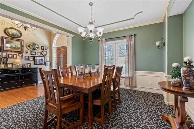 dining area featuring a wainscoted wall, crown molding, and an inviting chandelier