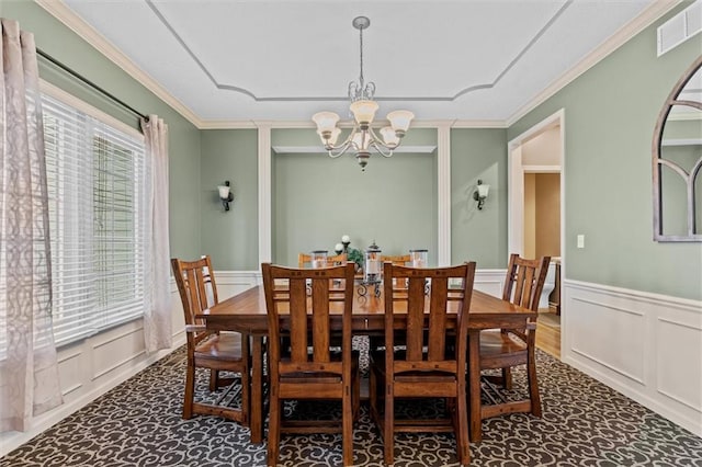 dining space featuring crown molding, visible vents, a notable chandelier, and a decorative wall