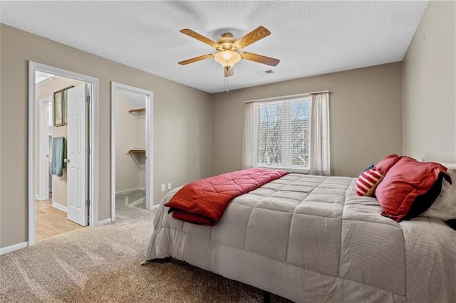 bedroom with visible vents, light colored carpet, a spacious closet, a textured ceiling, and baseboards