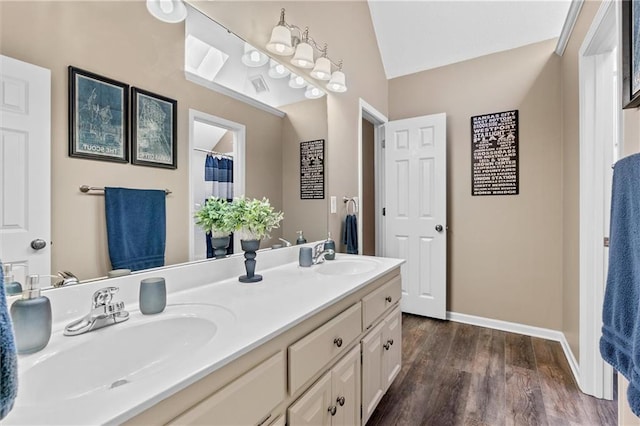 bathroom featuring double vanity, a sink, baseboards, and wood finished floors