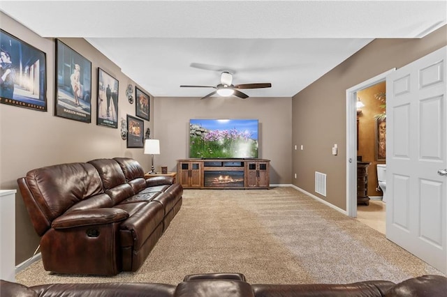 living room with visible vents, light carpet, ceiling fan, a lit fireplace, and baseboards