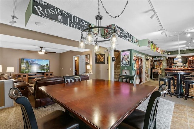 dining space with indoor bar, stairway, rail lighting, and a ceiling fan