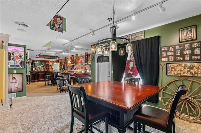 dining area featuring light carpet, visible vents, a bar, and a textured ceiling