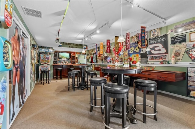 bar with track lighting, visible vents, light carpet, and a bar